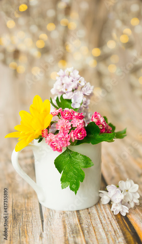 White cup with colorful flowers on wooden background