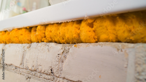 Polyurethane foam is used to install a plastic window. Yellow polyurethane foam for repair. View under the windowsill.