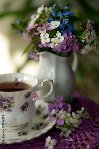 tea in a vintage china cup and flowers on a lilac knitted napkin
