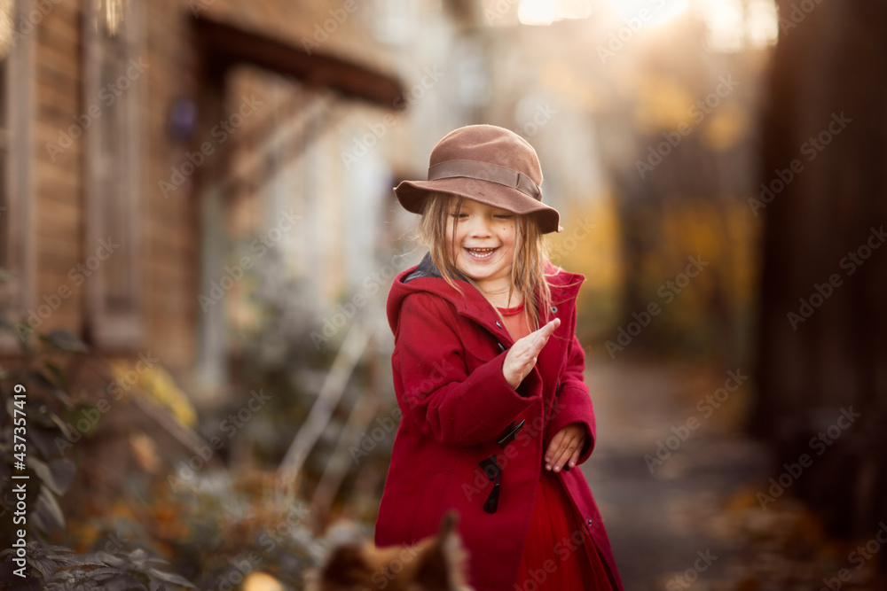 Cute funny caucasian child girl in red coat with dog in autumn street, children and animals