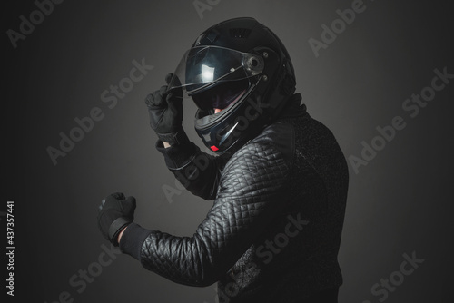 A motorbiker open a helmet visor on a gray background. © Dmitriy