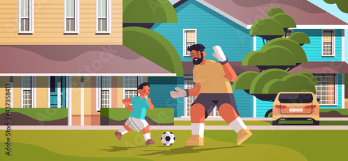 father playing football with son on backyard lawn parenting fatherhood concept dad spending time with kid