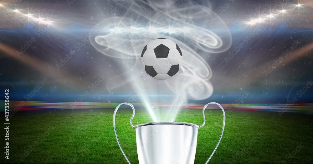 Compostion of cup and football over stadium and white smoke