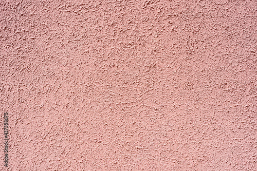 The rough surface of the light pink concrete wall