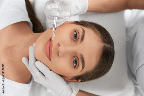 Top view of attractive young woman on procedure augmentation lips in beautician. Concept of special injection for improvements lips with cosmetics preparation.