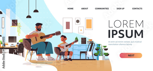 young father teaching little son to play the guitar at home parenting fatherhood concept living room interior