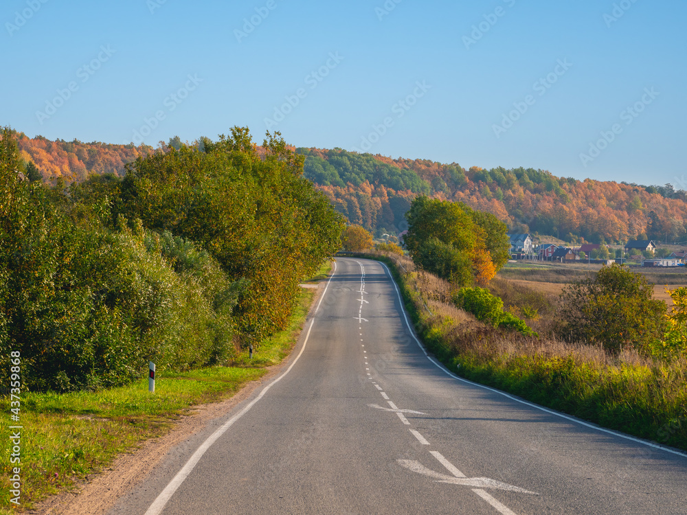 An empty highway country road among beautiful autumn hills.