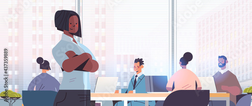businesswoman standing in front of mix race businesspeople coworkers discussing during conference meeting