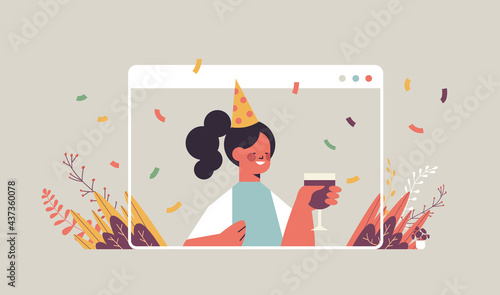woman in funny festive hat celebrating online birthday party happy girl in computer window drinking wine