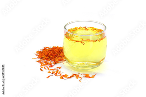 A glass of safflower tea and a pile of Dried Safflower petals herb Tea. isolated on a white background photo