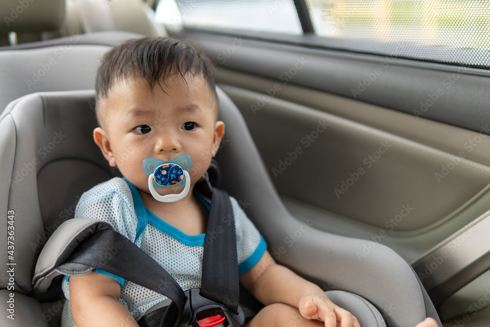 Local lifestyle Asian Chinese baby boy with emotion face and sucking pacifier while sit on child safety car seat Local lifestyle Asian Chinese baby boy with emotion face and sucking pacifier while sit on child safety car seat