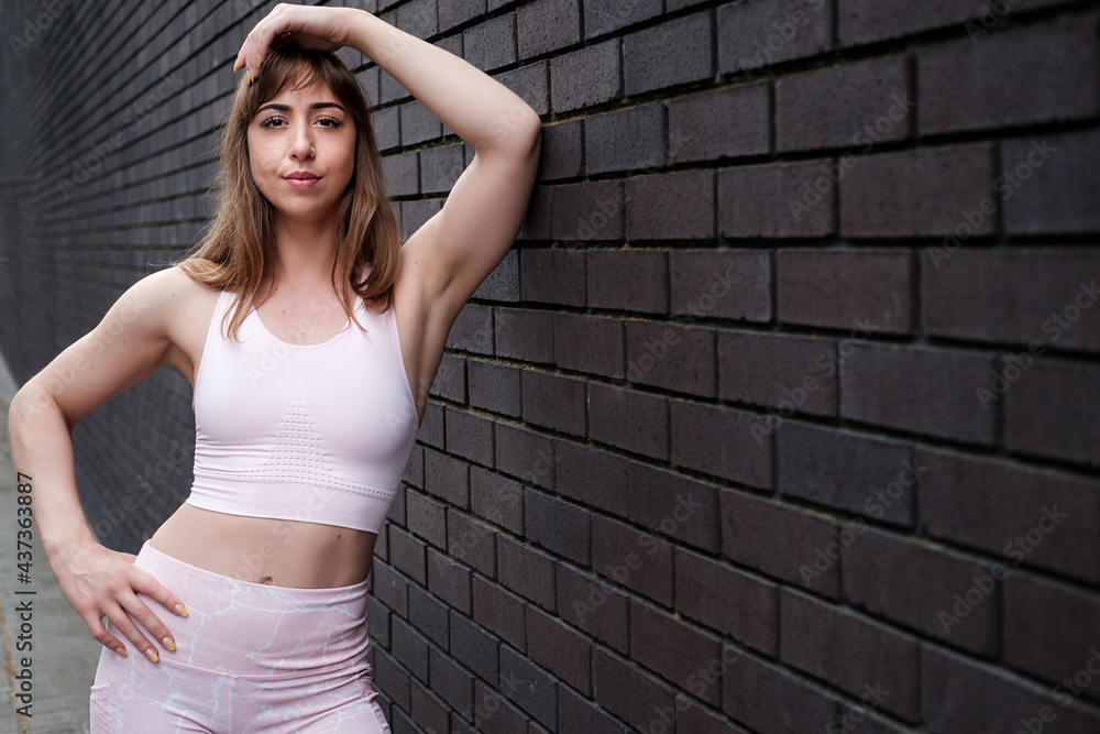 Young fitness woman posing on a brick background. Young fitness woman posing on a brick background.