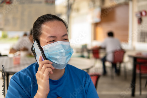 Local lifestyle Asian Chinese women Wearing Face Mask To Protect Her From Coronavirus Infection while waiting food on restaurant