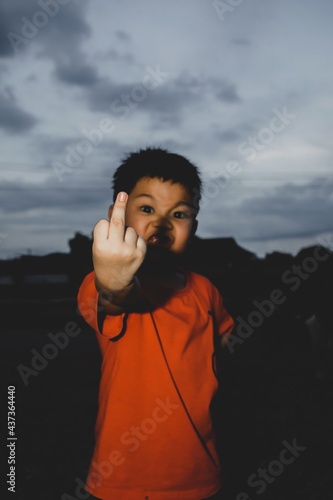Portrait of angry boy showing middle fingers doing fuck you bad expression.