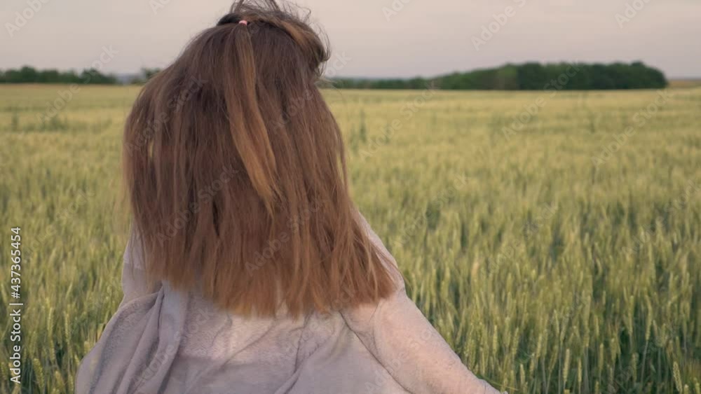 A happy child girl with long loose hair running under the open sky in a wheat field. The girl with her arms outstretched smiles and enjoys the fresh air. Childhood dream. A happy child girl with long loose hair running under the open sky in a wheat field. The girl with her arms outstretched smiles and enjoys the fresh air. Childhood dream.