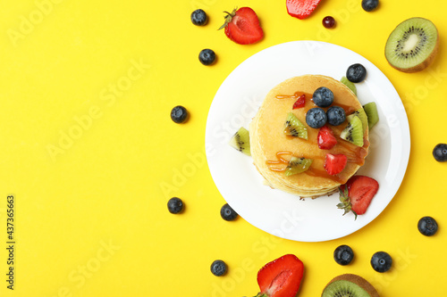Concept of delicious dessert with pancakes on yellow background