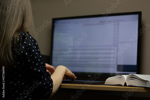 Closeup of a translator working with CAT (Computer-Assisted Translation) tool and dictionary.