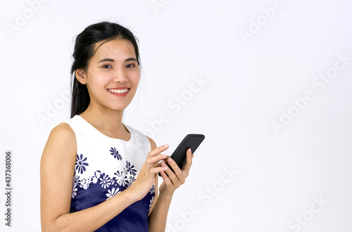 Young asian woman in white dress typing on a mobile phone. Portrait on white background with studio light.