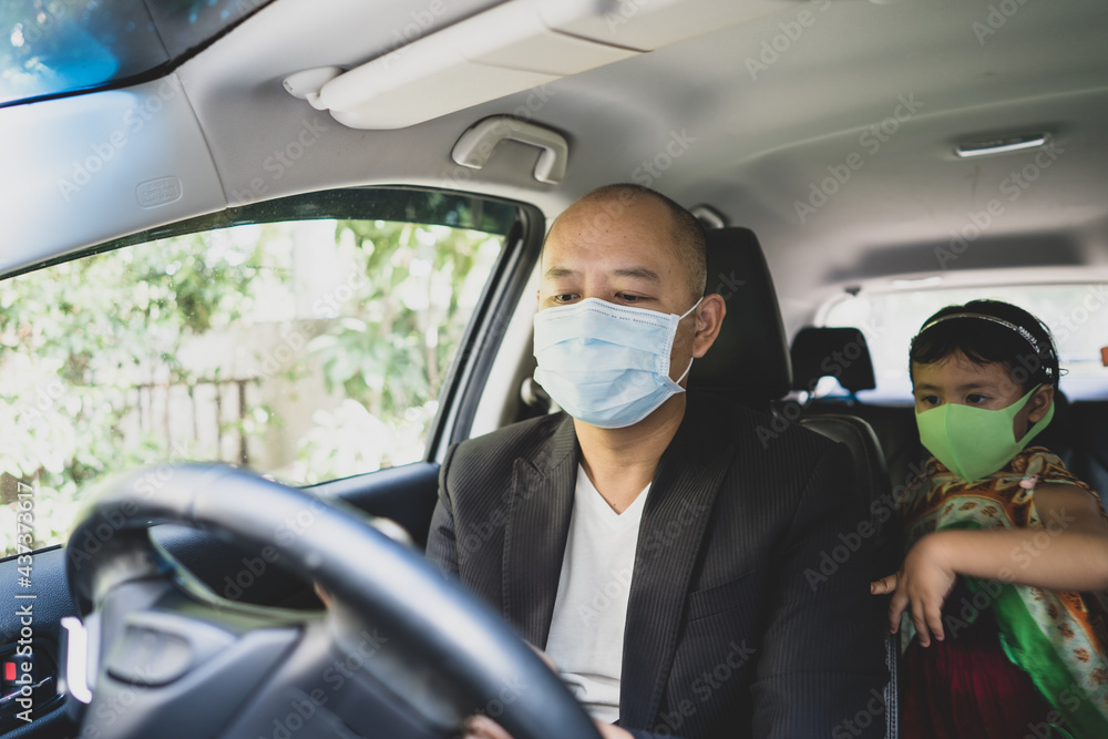 Father and daughter sitting in car wearing healthy face mask looking at smartphone. Father and daughter sitting in car wearing healthy face mask looking at smartphone.