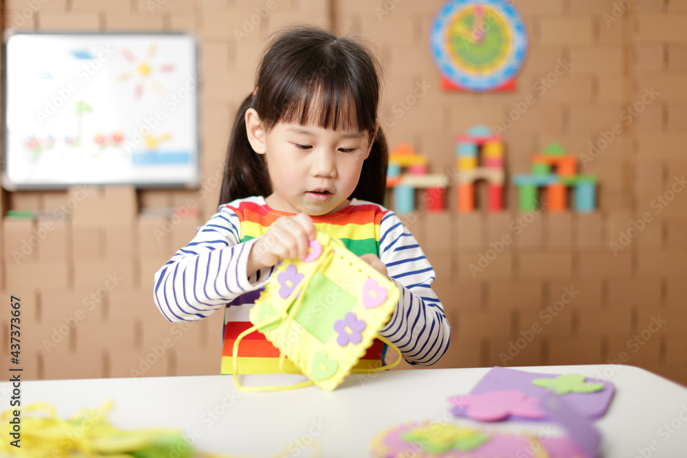 young girl sewing pad craft using plastic needle and yarn at home young girl sewing pad craft using plastic needle and yarn at home