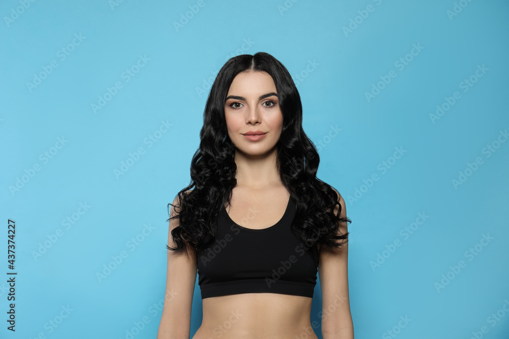 Beautiful young woman with long curly hair on light blue background Beautiful young woman with long curly hair on light blue background