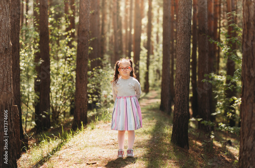 A cute little girl in glasses in nature on a sunny day © Olya Komarova