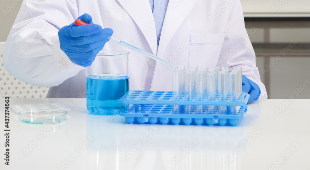 Scientist in blue shirt and lab coat do experiments in a scientific laboratory. Soft focus use for background. Scientist in blue shirt and lab coat do experiments in a scientific laboratory. Soft focus use for background.