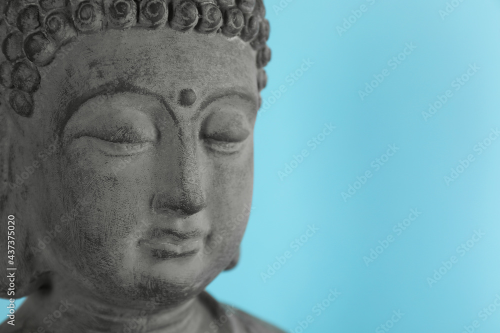 Beautiful stone Buddha sculpture on light blue background, closeup. Space for text