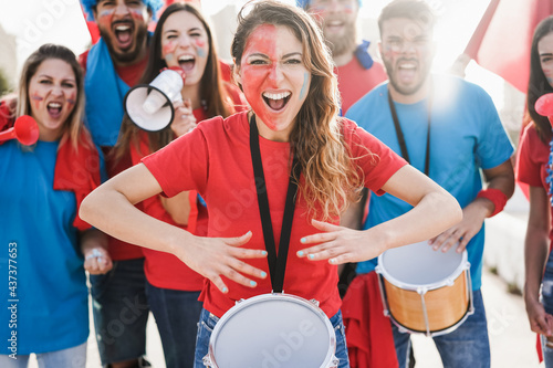 Crazy sport fans playing drums and screaming while supporting their team - Focus on center woman face