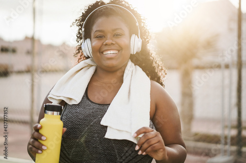 Sport curvy black girl listening music with headphones - Focus on face