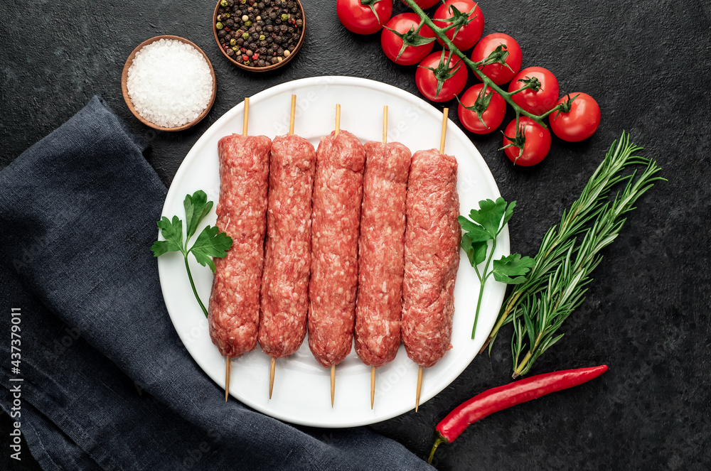 raw Lula kebab on skewers with spices on a stone background