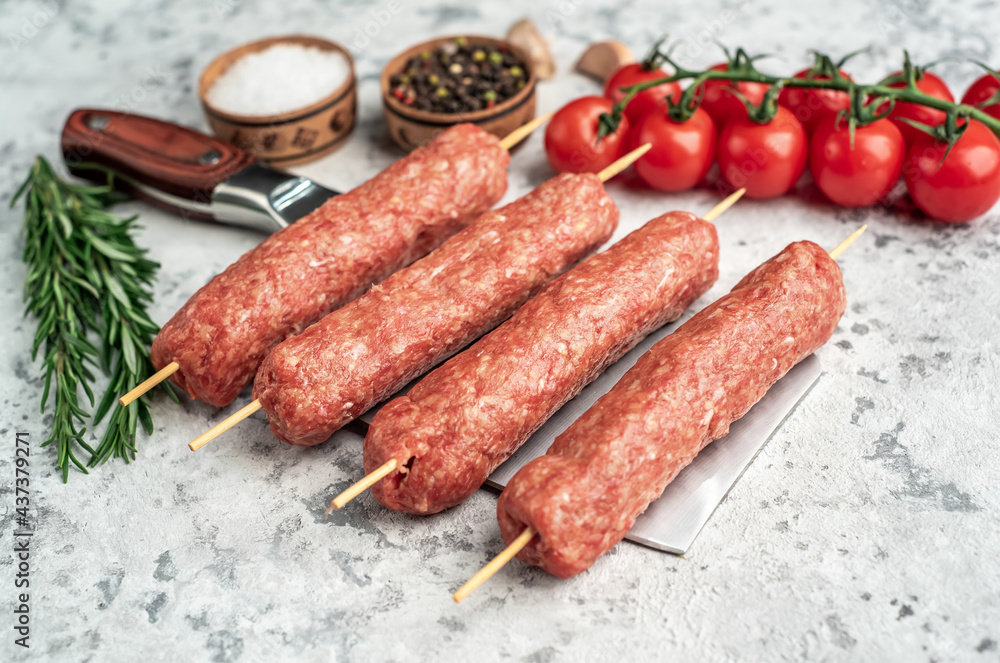 raw lula kebab on skewers with spices on a knife on a light stone background raw lula kebab on skewers with spices on a knife on a light stone background