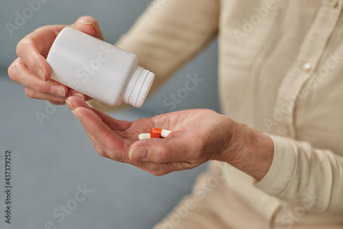 Senior woman taking daily medications at home during illness