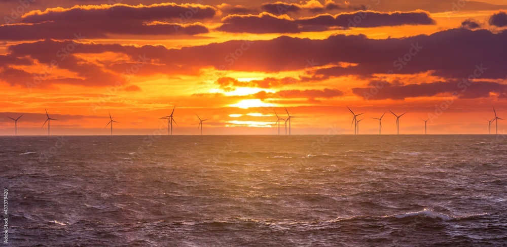Renewable green electricity wind power generation offshore. Sunrise at decarbonization industry windmills business for regenerative energies. Clean energy renewables preventing climate change Renewable green electricity wind power generation offshore. Sunrise at decarbonization industry windmills business for regenerative energies. Clean energy renewables preventing climate change