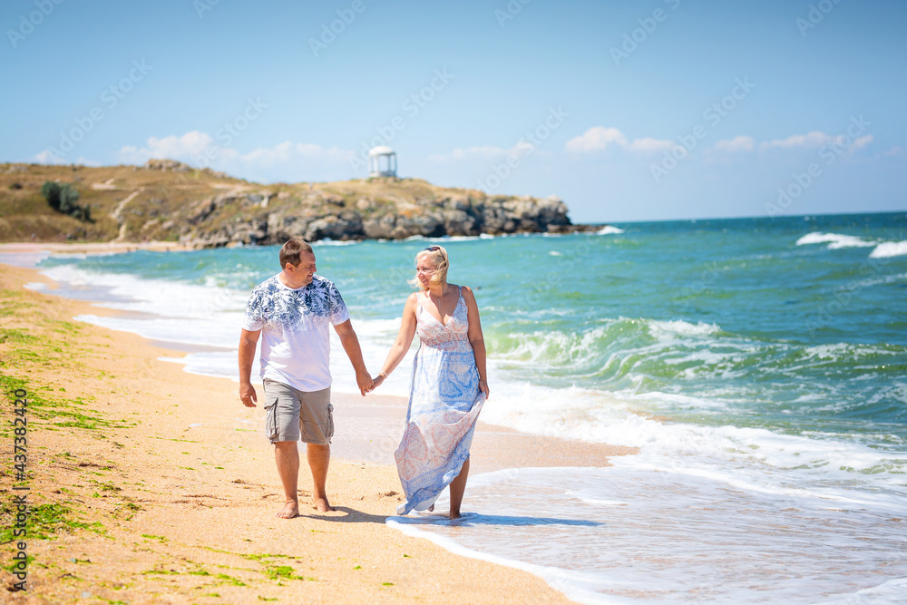 A couple of lovers, holding hands, walking on the beach. running on the water's edge, front view