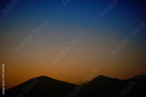 Mountains with night sunset sky with many stars, full moon rising. Night sky background