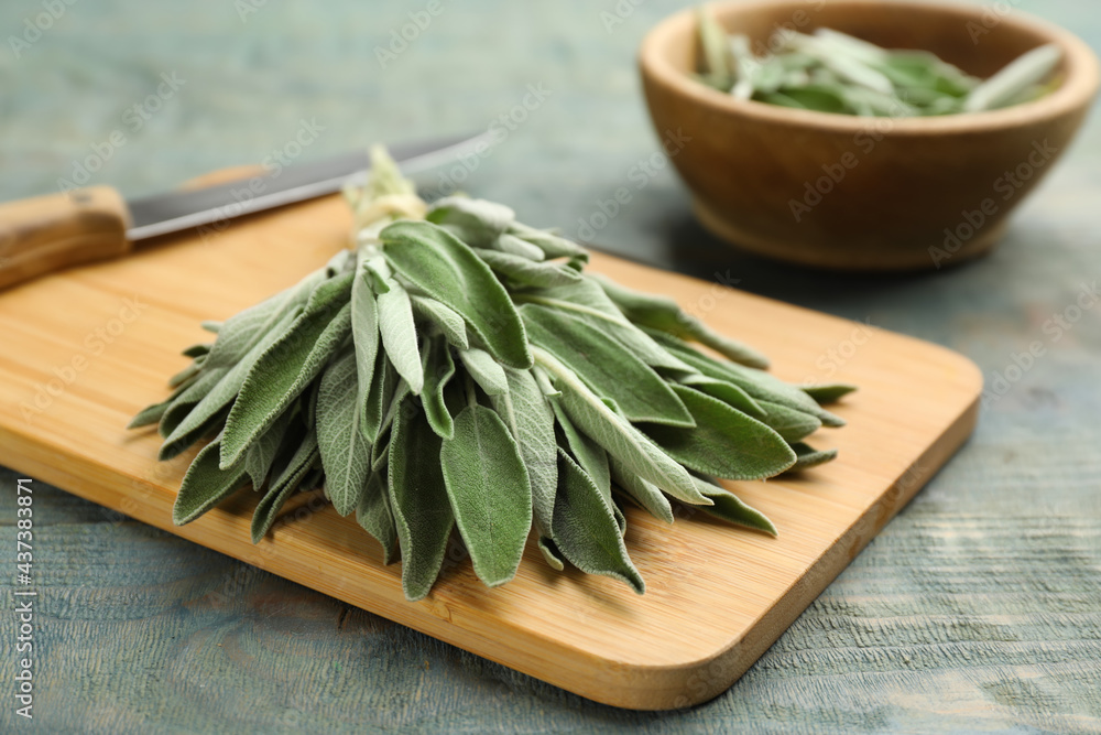 Wooden board with fresh green sage on light blue table, closeup Wooden board with fresh green sage on light blue table, closeup