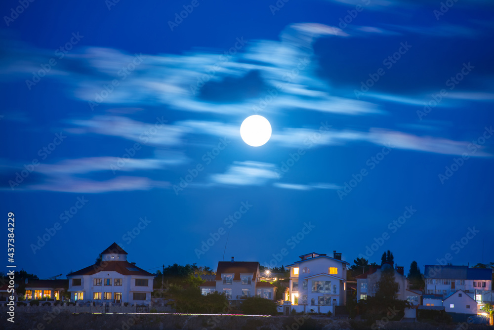 Moon over river and town with night sky and clouds