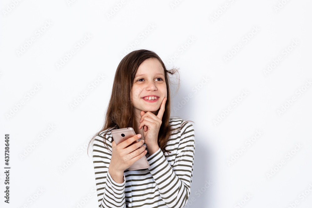 Funny dark-haired teenage girl smiles and communicates on the phone. Portrait on a light background Space for text Funny dark-haired teenage girl smiles and communicates on the phone. Portrait on a light background Space for text