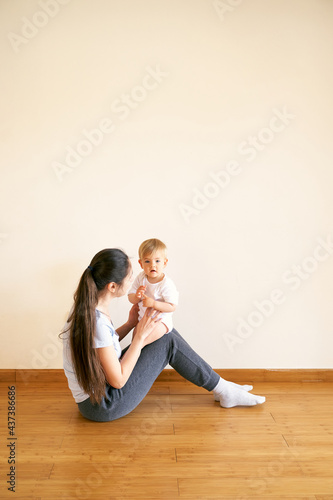 Mom keeps the baby on her knees on the floor in the room