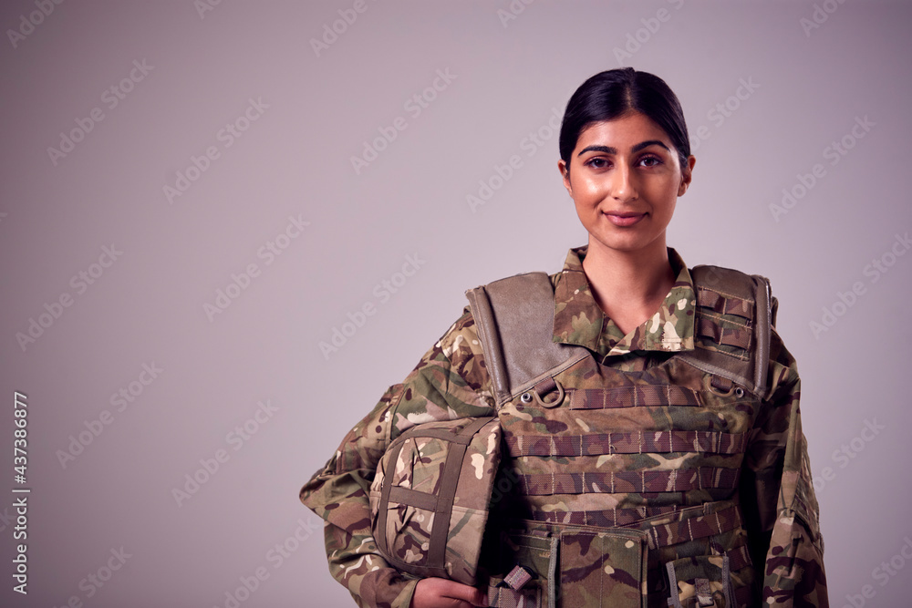 Studio Portrait Of Smiling Young Female Soldier In Military Uniform Against Plain Background Studio Portrait Of Smiling Young Female Soldier In Military Uniform Against Plain Background