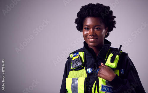 Tableau sur toile Studio Portrait Of Smiling Young Female Police Officer Against Plain Background