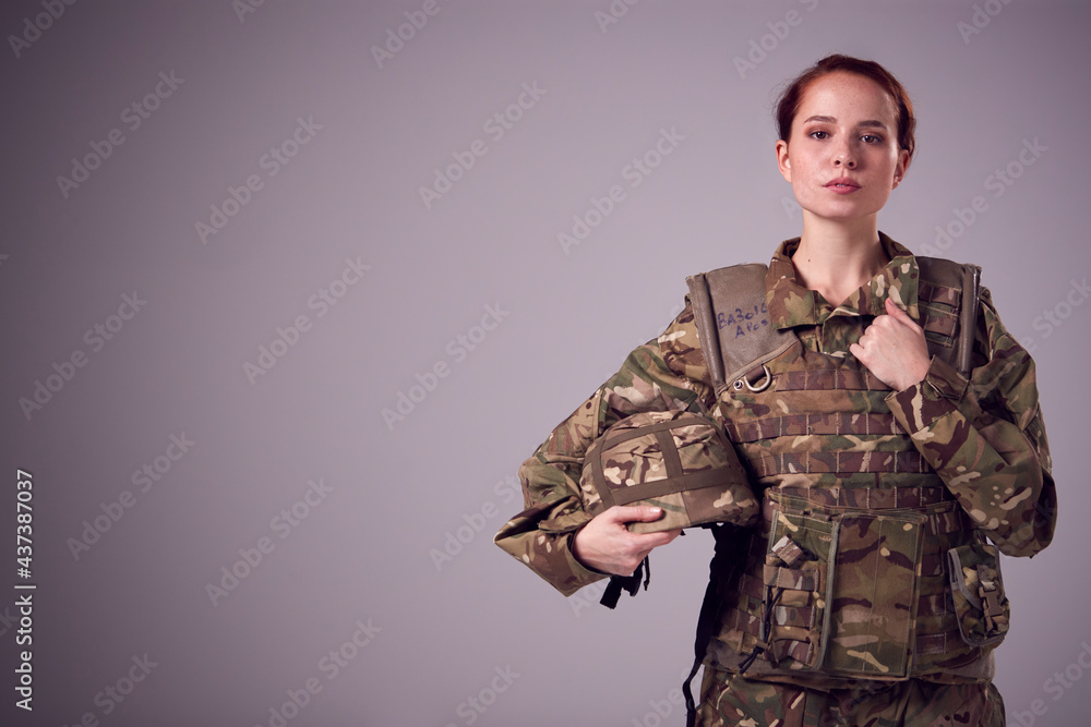 Studio Portrait Of Serious Young Female Soldier In Military Uniform Against  Plain Background Stock Photo