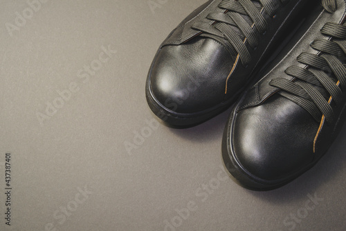 black mens shoes on a gray background. the shoes are at an angle to the horizon. place to insert text