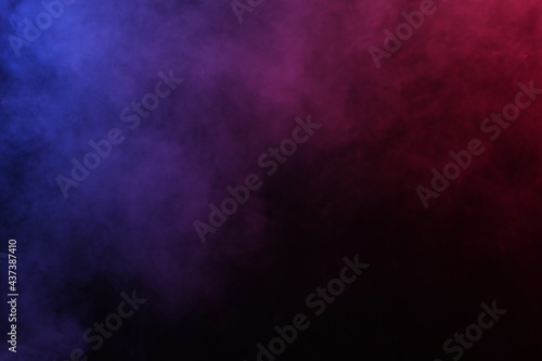 Artificial magic smoke in red-blue light on black background