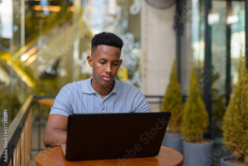 African businessman sitting at coffee shop while using laptop computer