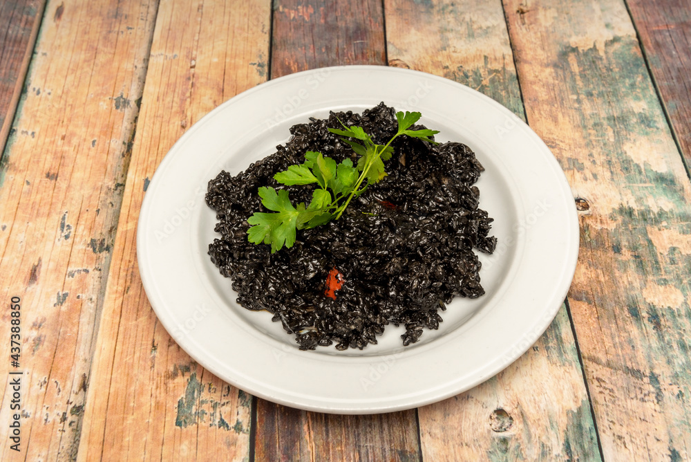 Portion of Spanish black paella with parsley on top to serve as tapas Portion of Spanish black paella with parsley on top to serve as tapas