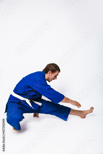Young man in a blue kimono on a white background. The guy is new to martial arts. © Вероника Преображенс