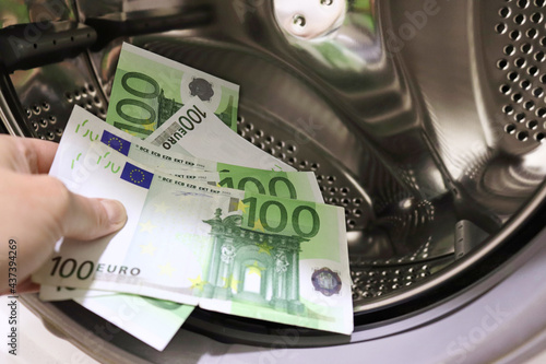 Money is put into the washing machine, close-up. Euro banknotes in washing mashine Money laundering. Money laundering