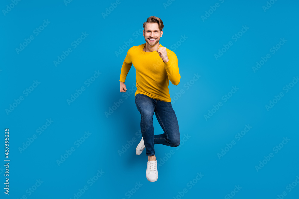 Full length body size photo of young man jumping high running fast cheerful careless isolated vivid blue color background